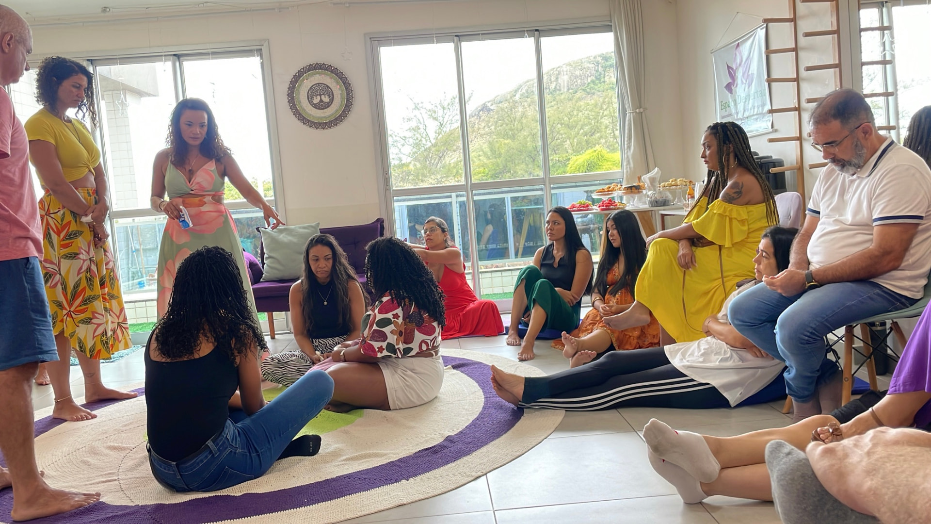 Kau Valéria falando para um grupo reunido em círculo em ambiente interno